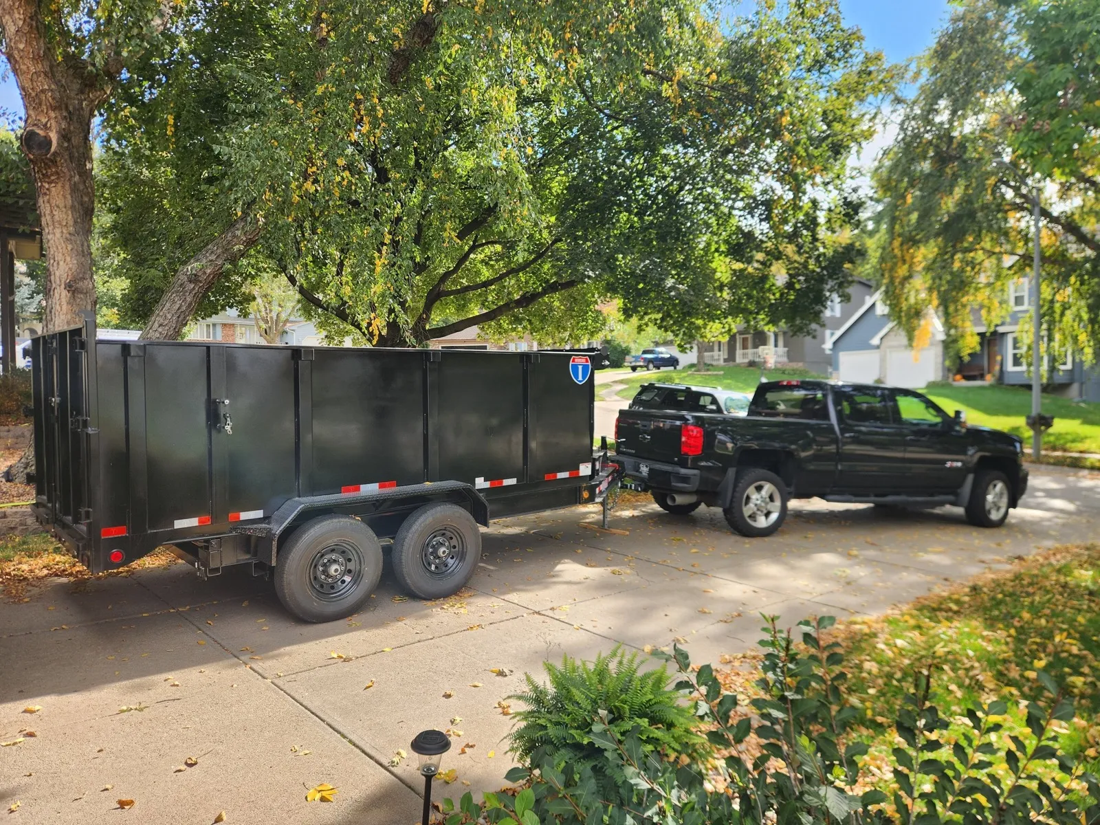Pickup truck and dump trailer staged in a driveway for a junk removal pickup