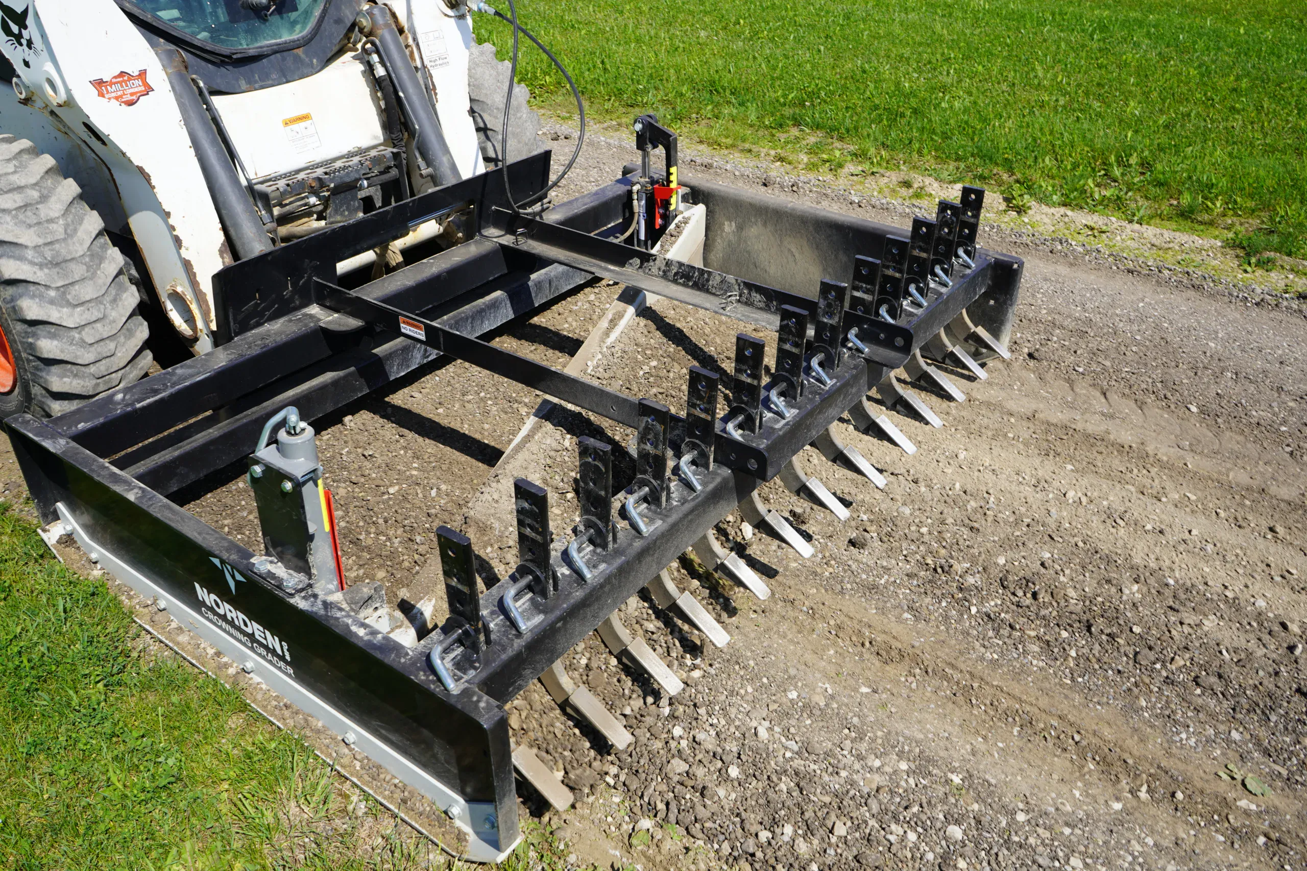 Skid steer with a rake attachment regrading a gravel driveway